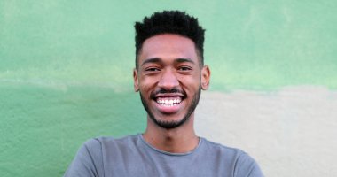 Mutlu genç siyah adam gülüyor ve gülümsüyor. Afrika kökenli gerçek hayat gülüyor ve gülümsüyor