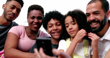 Mutlu melez aile telefon cihazına bakıp gülüyor ve gülümsüyor.