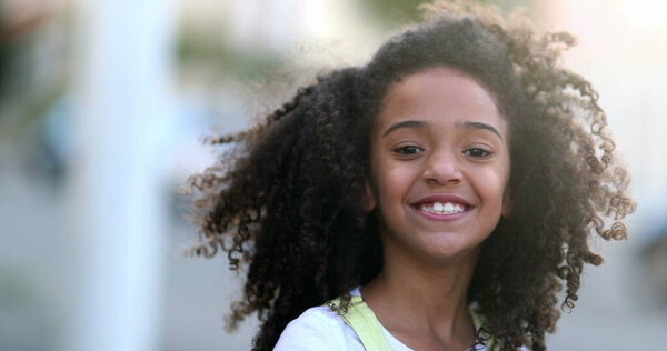 Happy female child smiling. Mixed race kid with curly hair and wind portrait face