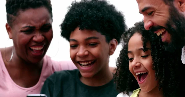 Happy family laughing together looking at cellphone at home