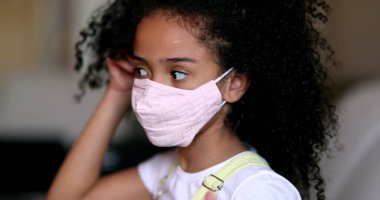 Covid-19 maskesi takan küçük bir kız. Portre çocuğu maske takıyor.