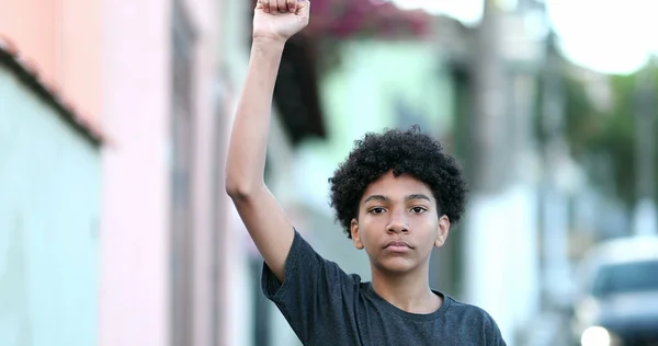 Little boy raises fist in air in protest. Mixed race child political protester raising fist