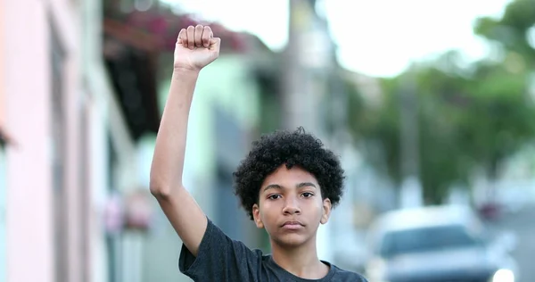 Little boy raises fist in air in protest. Mixed race child political protester raising fist