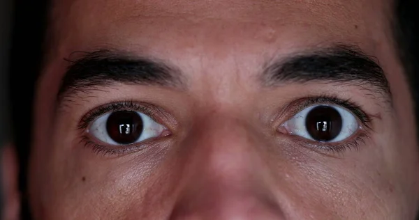 Man eyes staring camera, macro close-up man in 40s serious emotion
