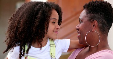 Karışık ırk anne ve kızı birlikte gülümsüyor.