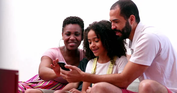 Multi-ethnic family using cellphone. Interracial parents and mixed race children looking at smartphone screen together