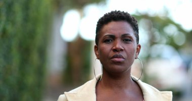 Ciddi bir Afrikalı kadın kaldırımda yürüyor.