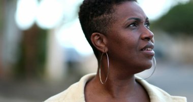 Sokakta yürüyen dalgın bir Afrikalı kadın. Düşünceli siyah bayan.