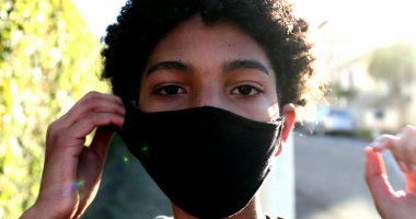 Sokakta Covid-19 maskesi takan genç bir çocuk.