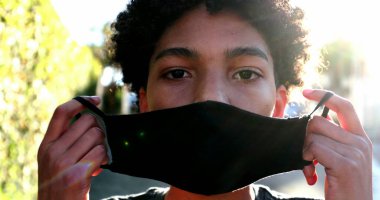 Sokakta Covid-19 maskesi takan genç bir çocuk.