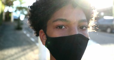 Sokakta Covid-19 maskesi takan genç bir çocuk.