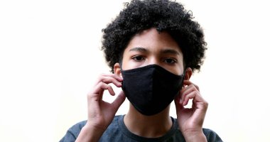 Young boy removing covid-19 face mask and feeling relief