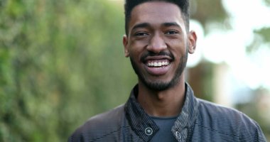 Young African man walking forward. Confident black ethnicity guy smiling portrait in motion