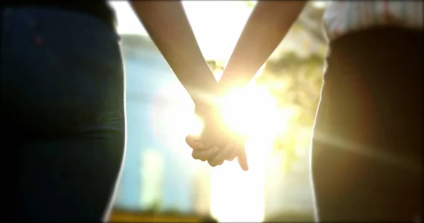 Close-up of hands joining together with sunlight flare in the background