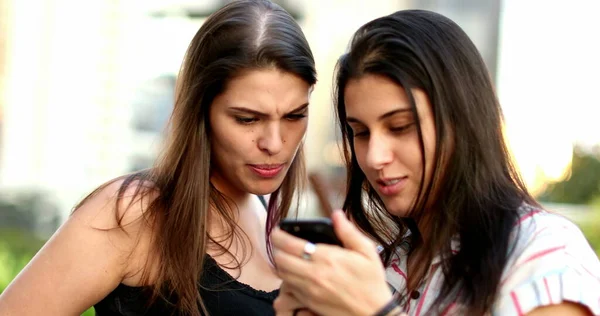 Candid Young Women Looking Smartphone Screen Girlfriends Checking Cellphone Frowning — стоковое фото