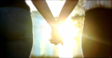 Hands joining together with sunlight flare in the background in 4K