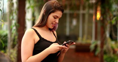 Kız dışarıda akıllı telefon aygıtı tutuyor.