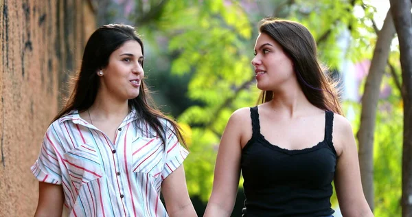 Kız arkadaşlar kaldırımda yürüyüp sohbet ediyorlar.