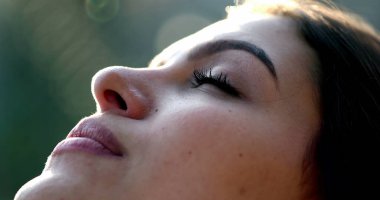Genç kadın, meditasyon ve tefekkürde gözlerini açarak gökyüzüne umutla ve inançla bakıyor.