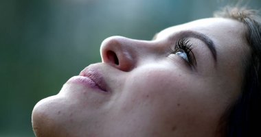 Genç kadın gözlerini kapatıp derin bir nefes alıyor, gökyüzüne bakıyor gözlerini açıyor ve meditasyonda gülümsüyor.