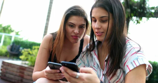 Young women checking smartphone together. Two girls using cellphone
