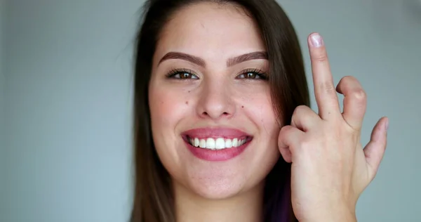 Young woman giving middle finger, pretty girl with attitude shows offensive gesture while smiling