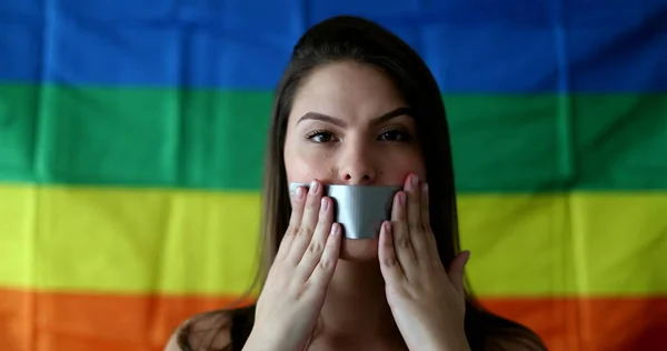 Young woman covering mouth with duct tape. LGBT censorship concept