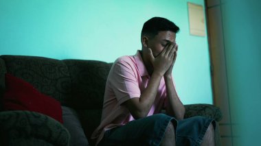 A frustrated young hispanic man covers face with hands feeling anxious. Preoccupied person