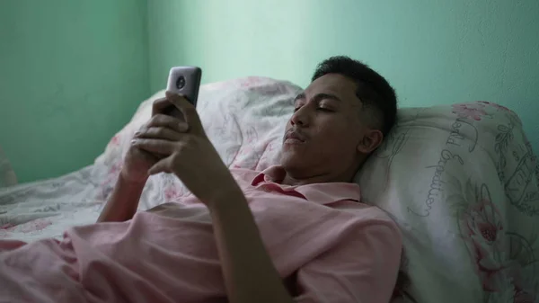 Young Hispanic Man Looking Cellphone Device Bedroom Lying Bed — Stock Fotó