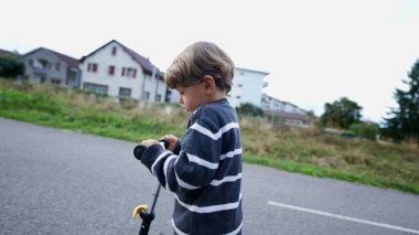 Child rides toy scooter outside