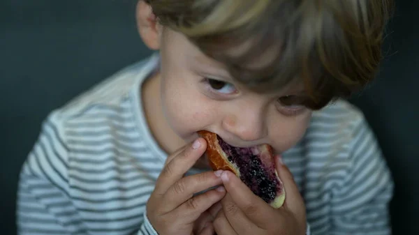 Toddler eating bread with jelly in morning breakfast