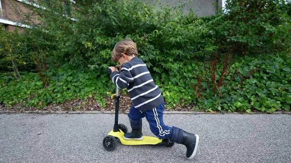 Little Boy Riding Three Wheeled Scooter Outdoors — Stockfoto