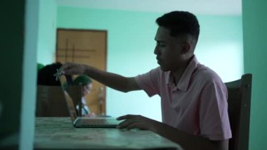 A hispanic man opening laptop screen and searching online at home