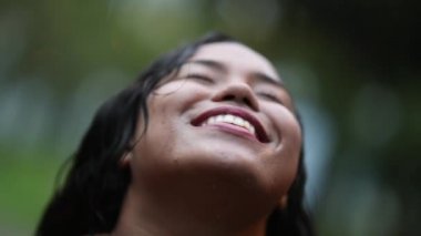 Dışarıda sağanak yağmur altında duran genç bir kadın. Özgürlüğü hisseden kız dışarıda yağmur yağıyor.