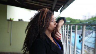 A pensive black woman thinking about life looking out from balcony home
