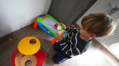Child development playing with toys in room by himself