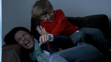 Toddler jumping on mother lying on sofa. Child jumps on top of mom in slow-motion