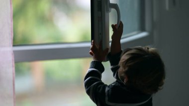Little boy opening home window letting fresh air enter