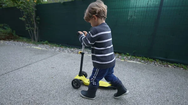 Toddler walking outside with scooter toy