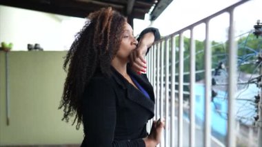 Düşünceli bir kadın evde balkonda dikilip dışarıyı seyrediyor.