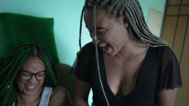 Three hispanic friends laughing together. Candid group of people smiling sitting on couch