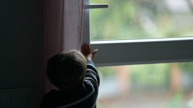 Child closing window. Toddler closes window