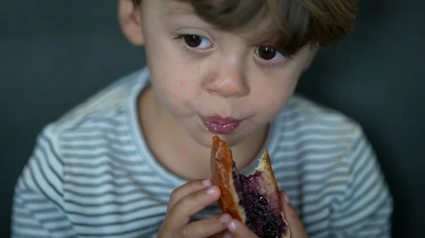 Toddler eating bread with jelly in morning breakfast