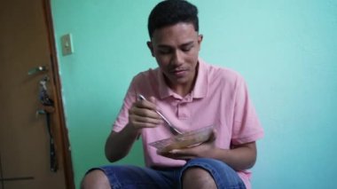 Brazilian man eating lunch at home. One latin hispanic person eats food