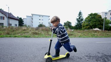 Child rides toy scooter outside