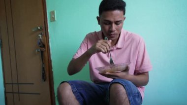 South American man eating lunch at home. A Brazilian hispanic person eats pasta