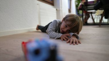 Little boy lying on floor playing with toy at home