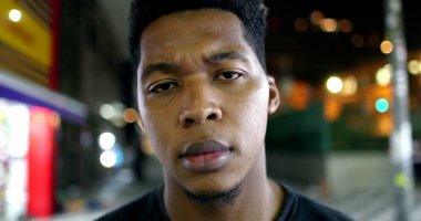 African male standing outside in city looking at camera with serious face