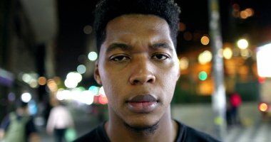 African male standing outside in city looking at camera with serious face