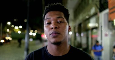 African male standing outside in city looking at camera with serious face